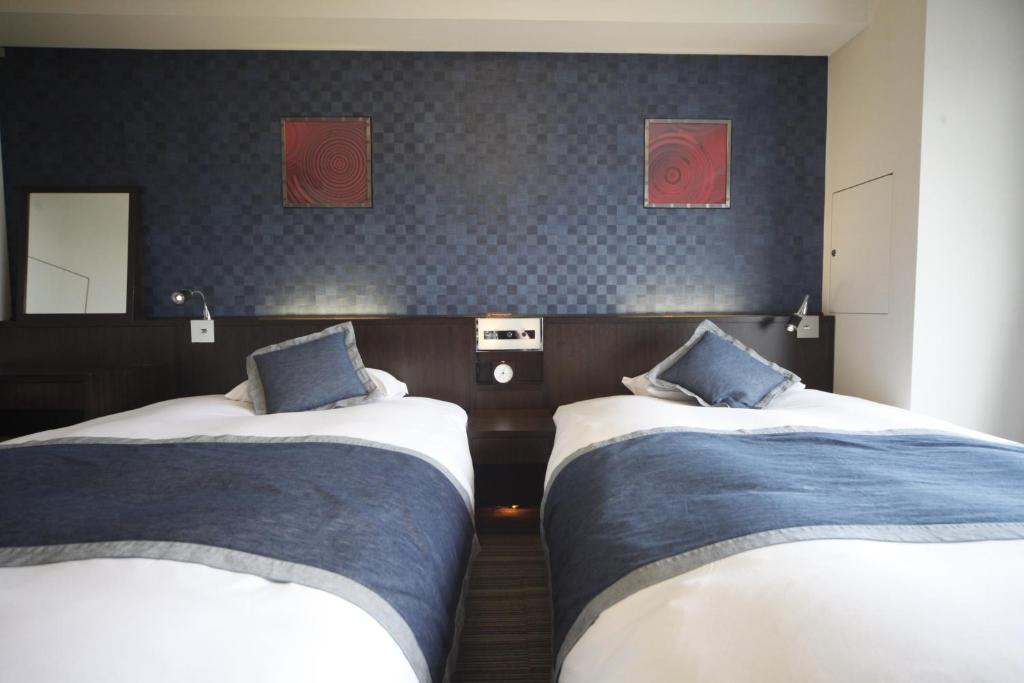 a room with two beds in a room with two mirrors at Via Inn Asakusa in Tokyo