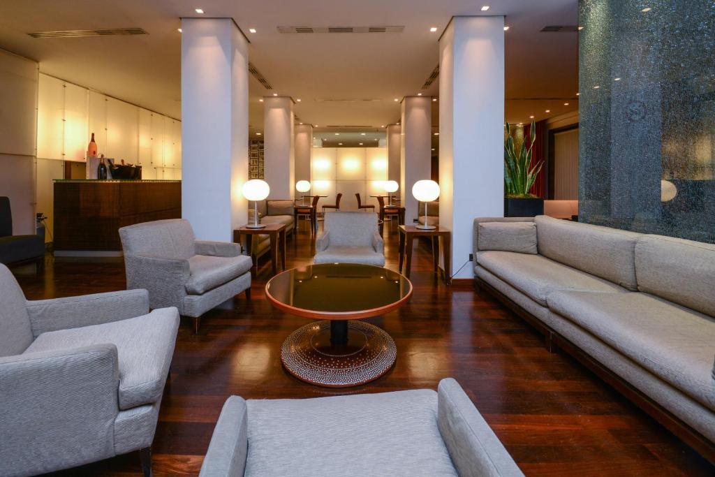 a lobby with couches and a table and chairs at Hotel Igea in Brescia