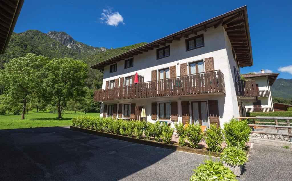 a large white building with a balcony and some bushes at Casa Lori Green Holiday in Ledro