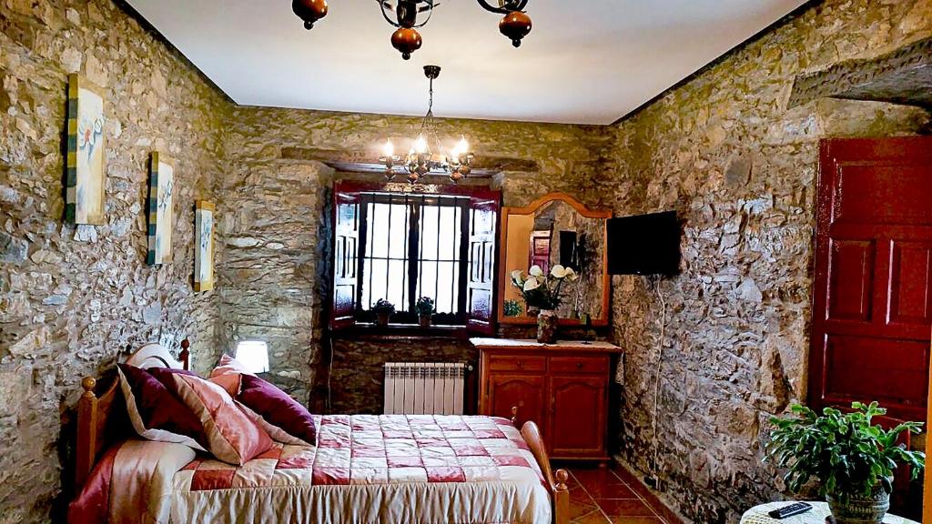 1 dormitorio con cama y pared de piedra en La Casona de Faedo Pensión, en Faedo