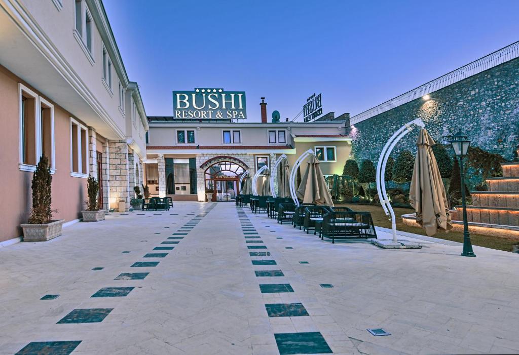 a building with chairs and umbrellas in a courtyard at Bushi Resort & SPA in Skopje