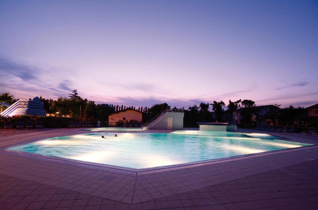 a large swimming pool at night with the lights on at Villaggio San Francesco in Duna Verde