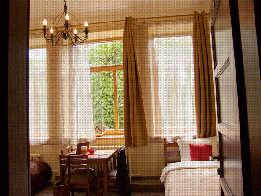 a bedroom with a bed and a table and a window at Hostel Lux in Kaunas
