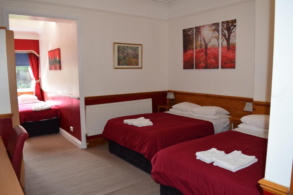 a hotel room with two beds with red sheets at Heatherbank Guest House in Barnet