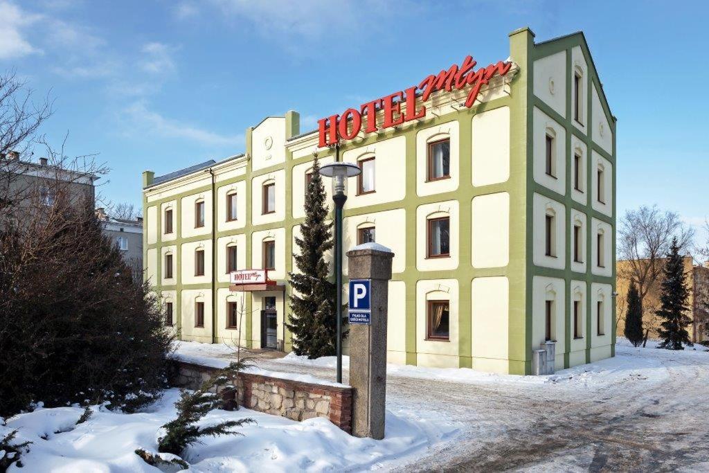 un grand bâtiment jaune avec un panneau d'hôtel dans la neige dans l'établissement Hotel Młyn, à Lublin