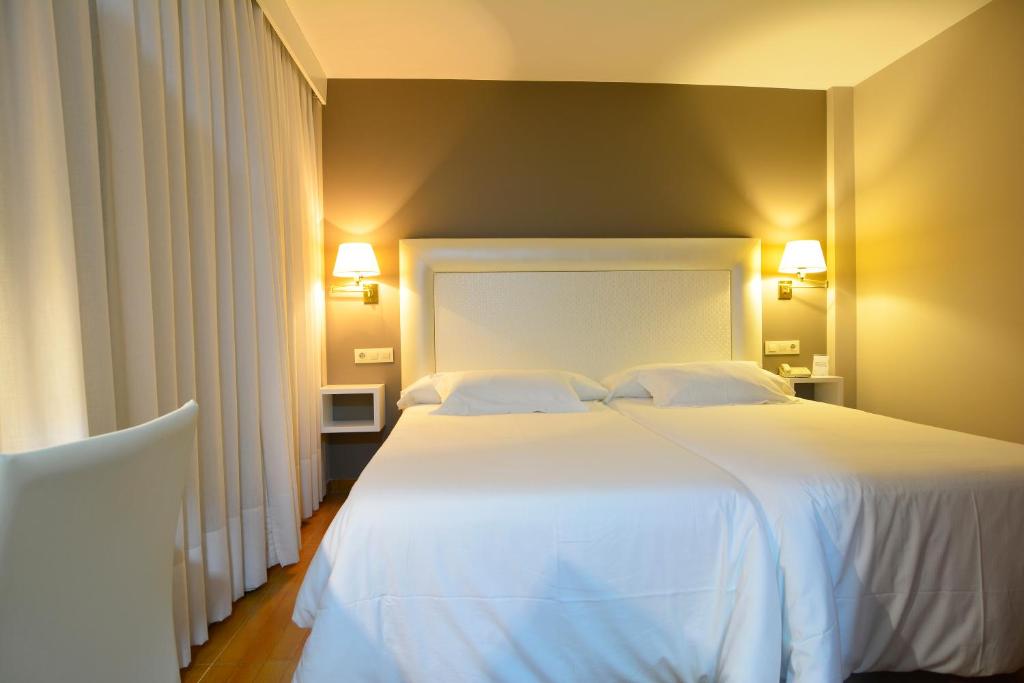 a bedroom with a large white bed with two pillows at Hotel Jucamar in Cangas de Morrazo
