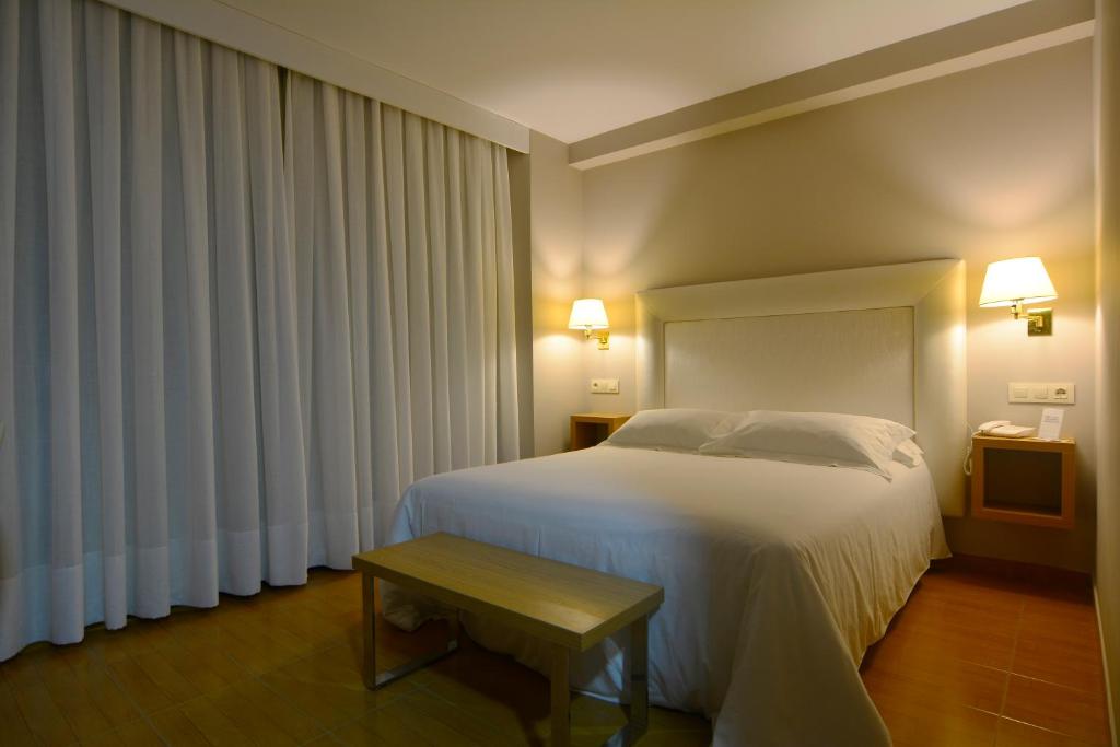 a bedroom with a white bed and a table at Hotel Jucamar in Cangas de Morrazo