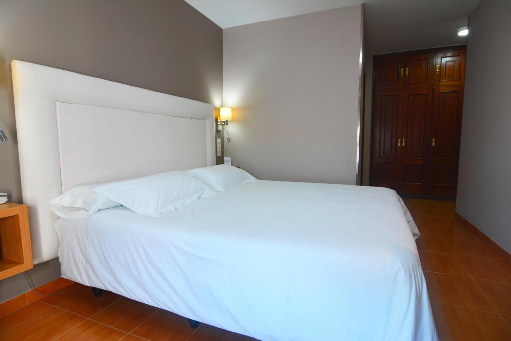 a bed with white sheets and pillows in a bedroom at Hotel Jucamar in Cangas de Morrazo