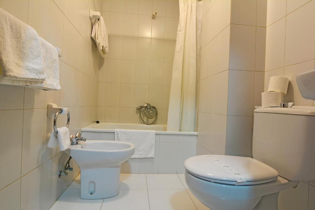 a white bathroom with a toilet and a sink at Hotel Jucamar in Cangas de Morrazo