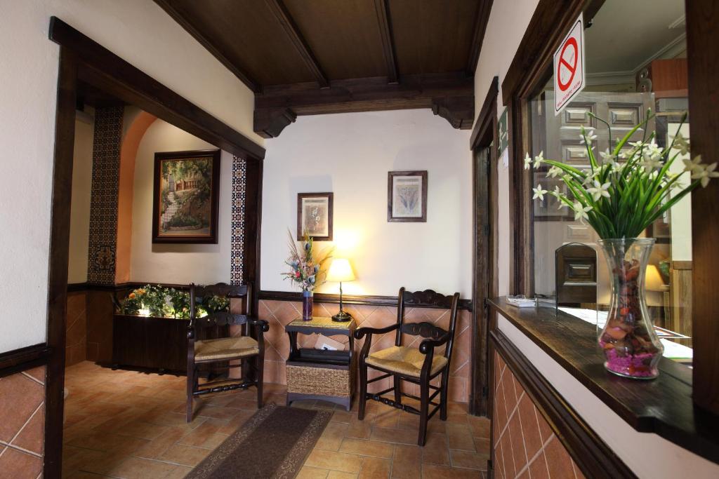un vestíbulo con una mesa y sillas y un jarrón de flores en Hostal Rocio, en Sanlúcar la Mayor