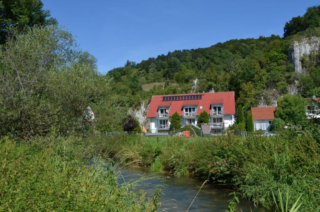 um edifício com um telhado vermelho ao lado de um rio em Ferienwohnungen Holder em Anhausen