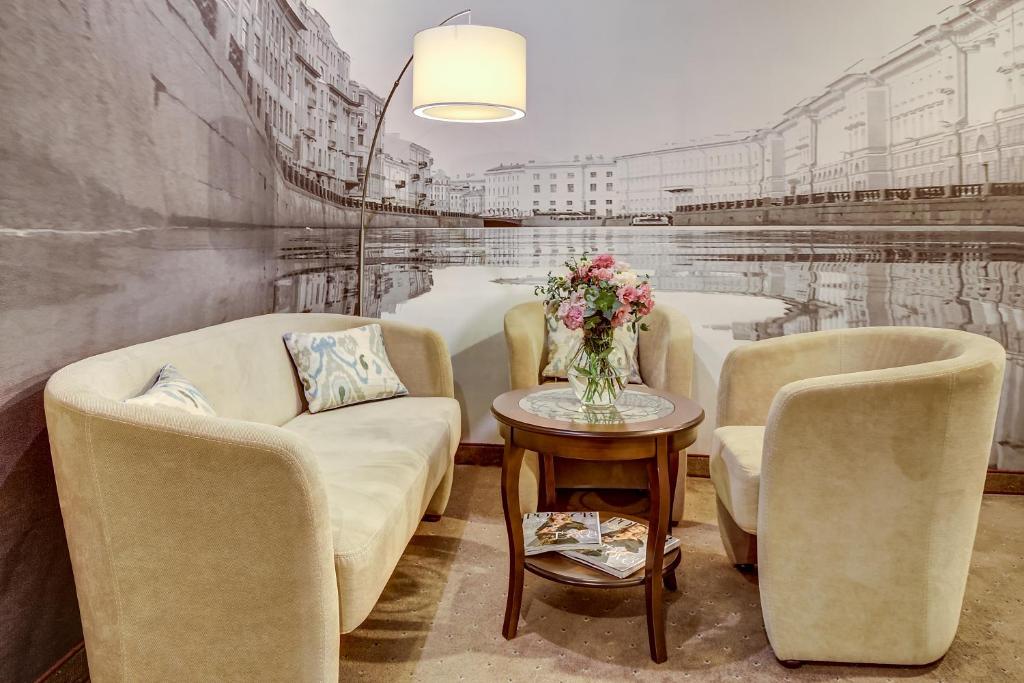 a living room with two couches and a table with flowers at Pushka INN hotel in Saint Petersburg