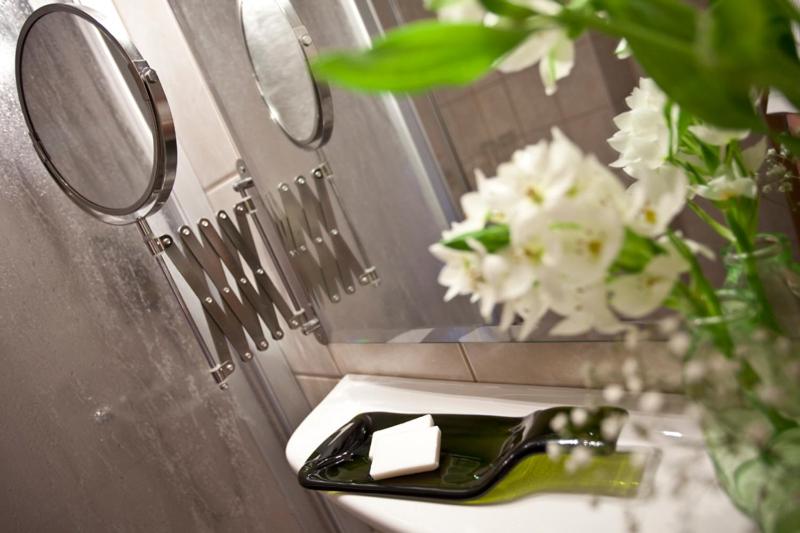 een wastafel in de badkamer met een spiegel en een vaas met bloemen bij Nationalparkhotel Kranichrast in Schwarzenhof