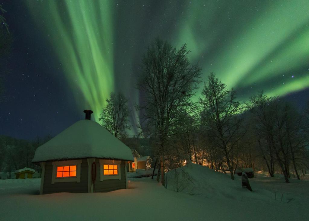 un iglú bajo la aurora en la nieve por la noche en Lohi-Aslakin Lomamökit, en Utsjoki
