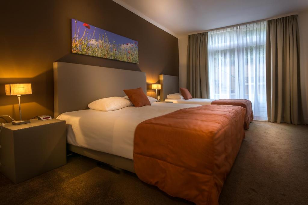 a hotel room with two beds and a large window at Appartementen Valkenburg in Valkenburg