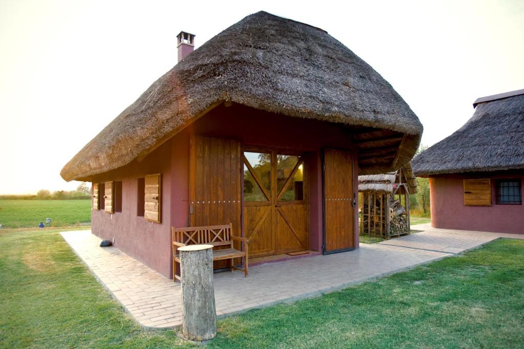 Cette petite maison dispose d'un toit de chaume et d'une terrasse couverte. dans l'établissement Agriturismo Bassara Le Capanne, à Argenta