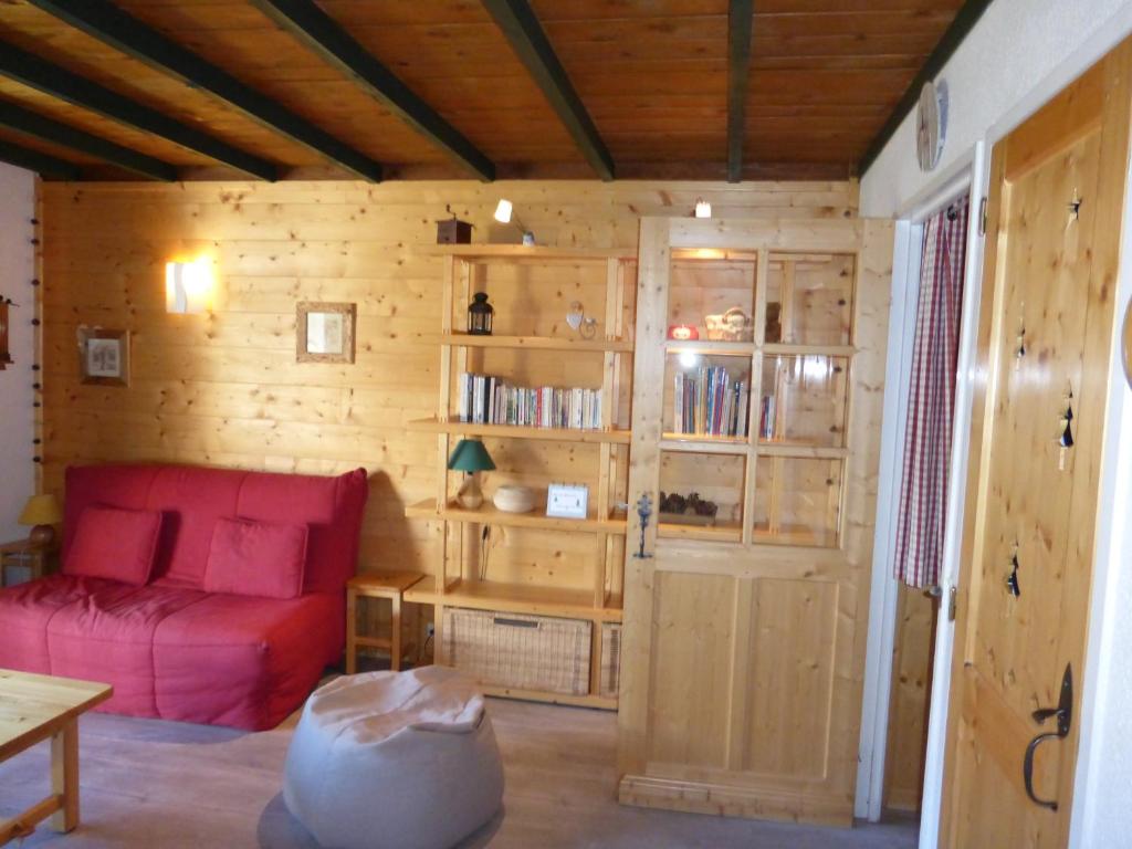 sala de estar con sofá rojo y paredes de madera en Chalanche, en Barcelonnette