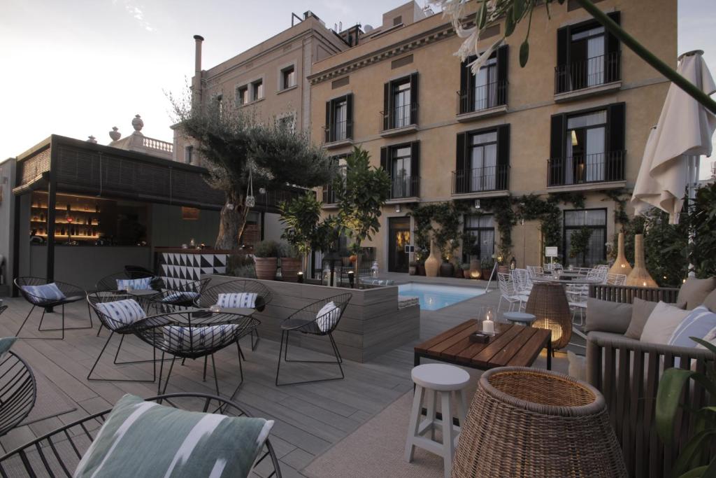 um pátio no último piso com mesas e cadeiras e uma piscina em Hotel Oasis em Barcelona