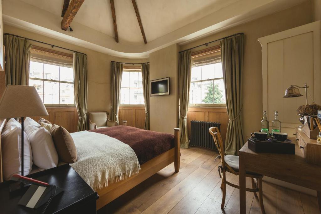 a bedroom with a bed and a desk and windows at The Orange in London