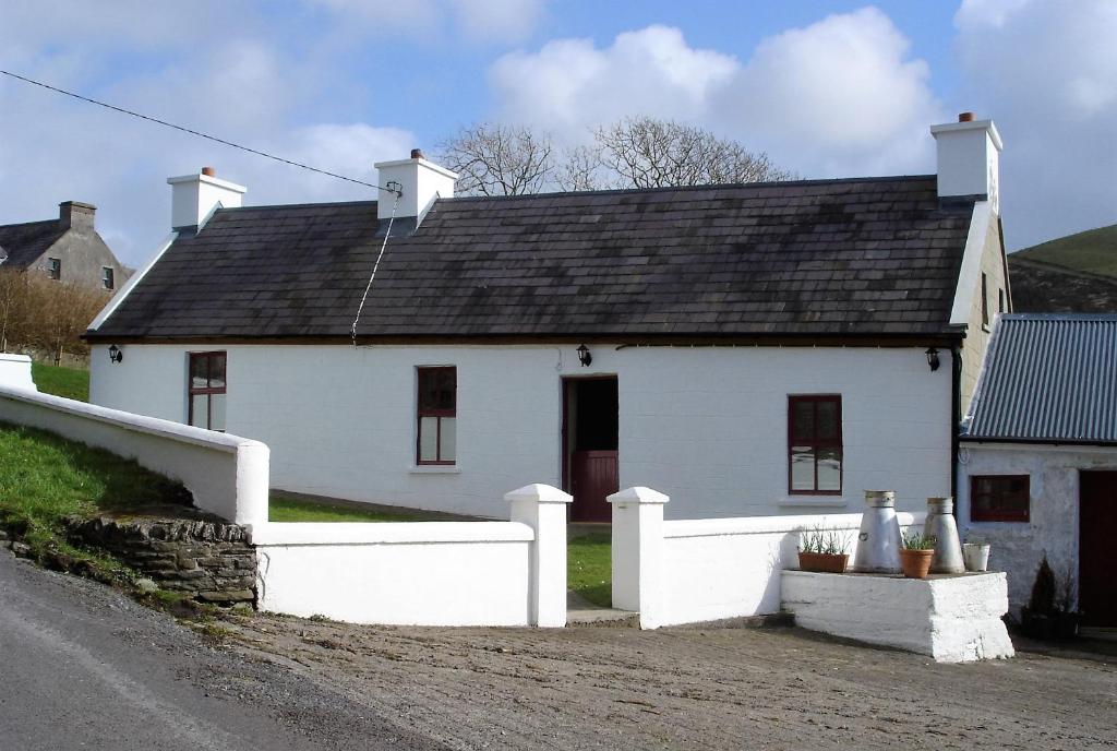 a white house with a black roof on a street at Griffins Holiday Cottage in Dingle