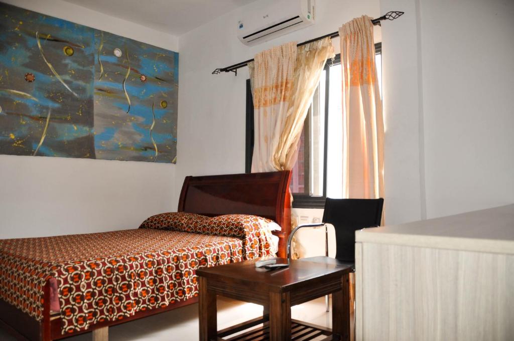 1 dormitorio con 1 cama, 1 silla y 1 ventana en Guest House Lumen en Lomé