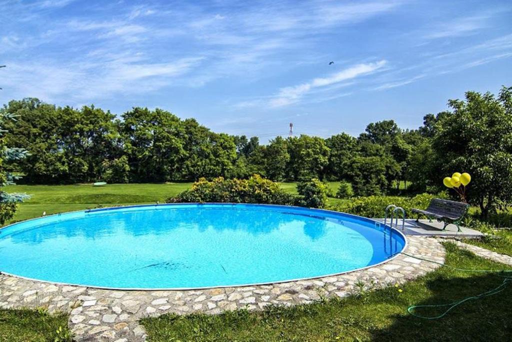 a large blue swimming pool in a yard with a bench at Kaštieľ AGATKA in Chorvátský Grob