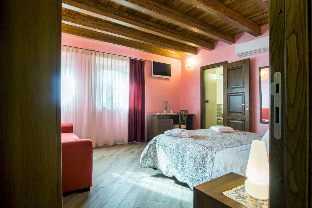 a bedroom with a bed and a red chair at L'Arco dei Sogni in Malvagna