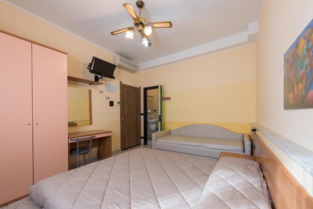 a bedroom with a bed and a desk and a ceiling fan at Hotel Santa Maria in Finale Ligure