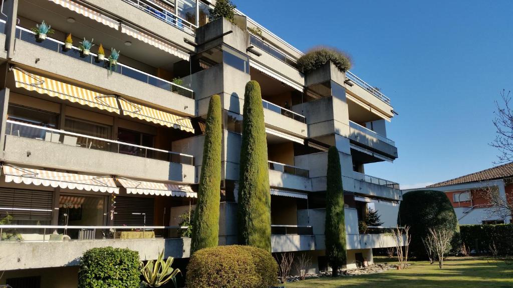 um prédio de apartamentos com árvores em frente em Ferienwohnung "Casa Annabella" em Ascona