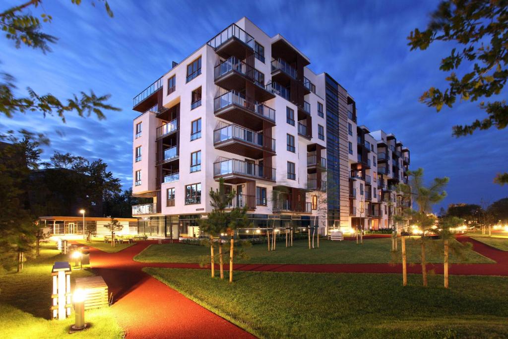 a large white building with trees in front of it at Apartamenty Olimpic in Kołobrzeg