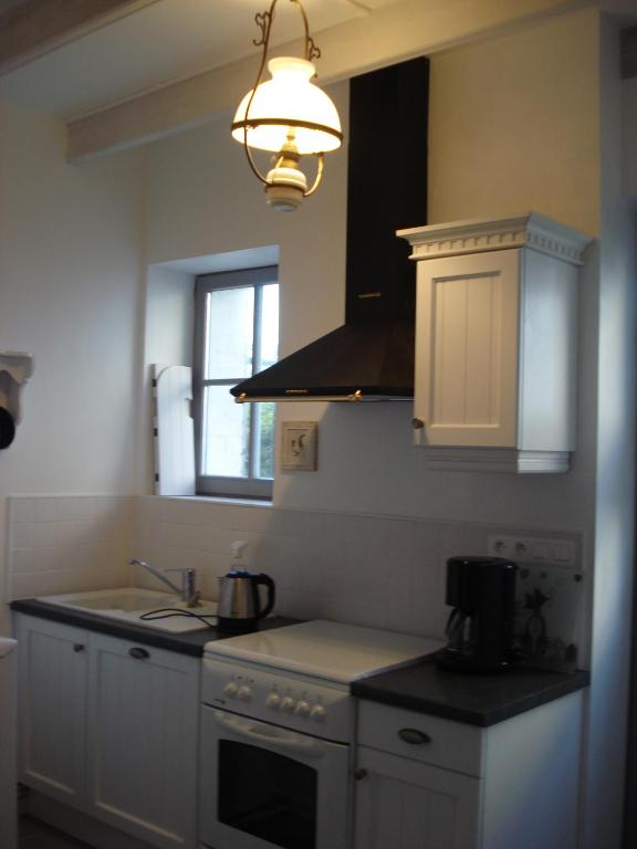 une cuisine avec un évier et une cuisinière four supérieur dans l'établissement La Petite Maison du Parc, à Bois-en-Ardres