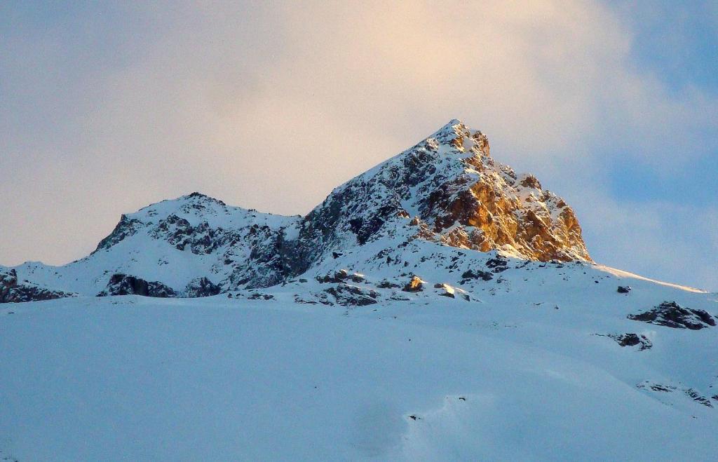 una montaña cubierta de nieve con el sol brillando sobre ella en Ferienwohnung Stoffel en Cresta