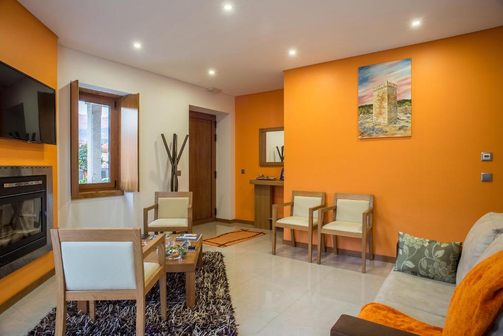 Wohnzimmer mit orangefarbenen Wänden, Sofa und Stühlen in der Unterkunft Quinta de Remoães in Melgaço