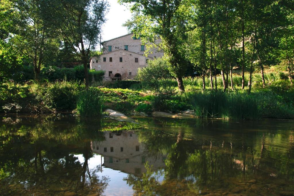 une vieille maison se reflète dans l'eau d'une rivière dans l'établissement Mulino Della Ricavata, à Urbania