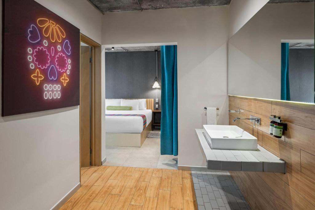 A bright bathroom opens directly toward a bedroom, with a wide vanity and vessel sink.