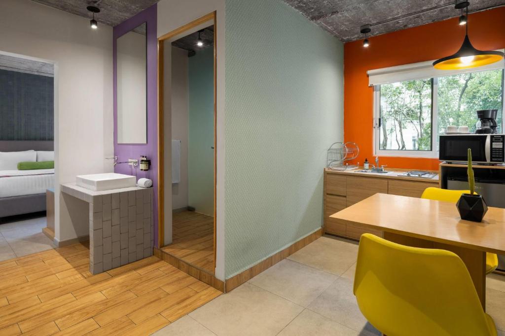 A compact suite-style kitchen and dining area beside an open vanity and bedroom.