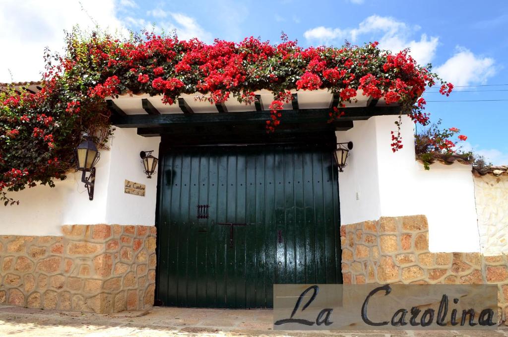 una puerta verde con flores rojas en la parte superior de un edificio en Casa La Carolina, en Villa de Leyva