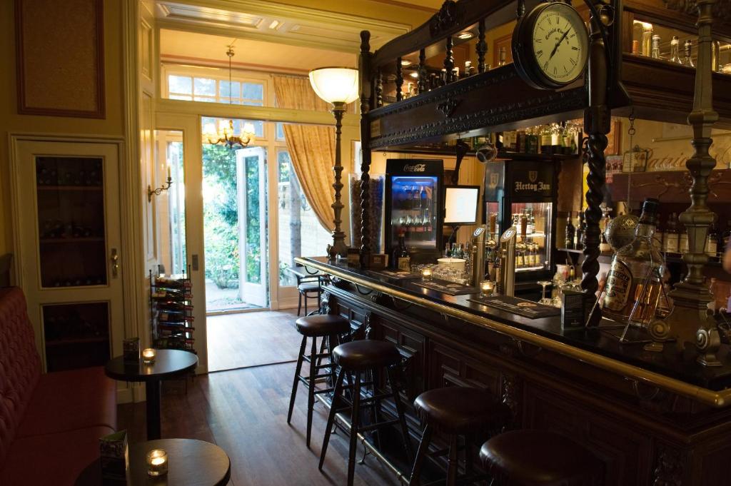 een bar met krukken en een klok aan de muur bij Hotel Fidder - Patrick's Whisky Bar in Zwolle