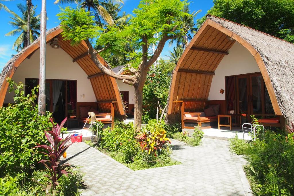 een huis met een rieten dak en een patio bij Chill Out Bungalows in Gili Air