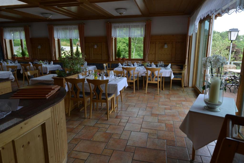 ein Esszimmer mit weißen Tischen, Stühlen und Fenstern in der Unterkunft Landhaus Waldfrieden in Tengen
