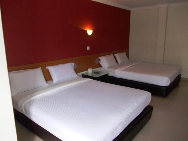 Lotus Hotel Johor Bahru في جوهور باهرو: سريرين في غرفة الفندق بسريرين