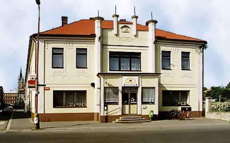 a white building with an orange roof on a street at Penzion Česká Koruna in Čáslav