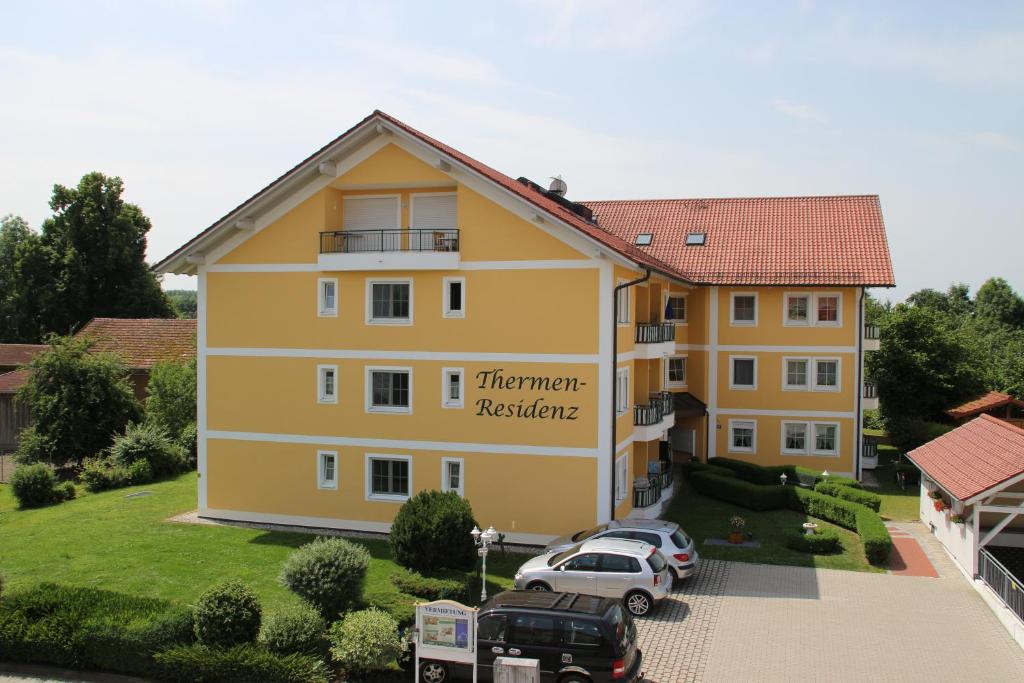 a large yellow building with cars parked in a parking lot at 2 Zimmer Kursuite Bad Füssing in Bad Füssing