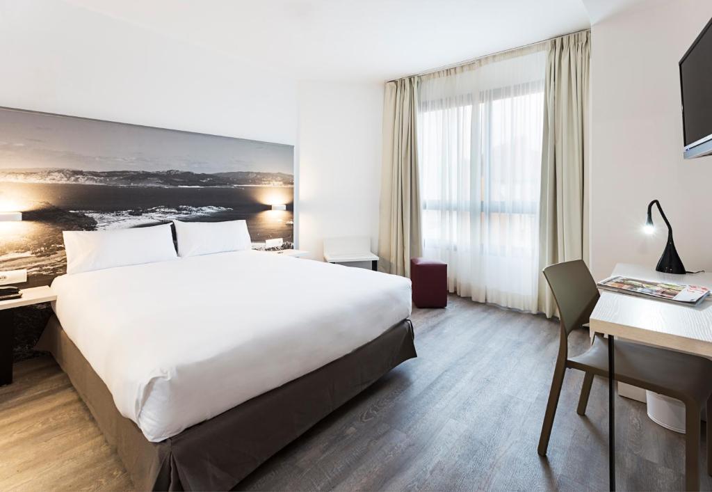 ein Hotelzimmer mit einem großen Bett und einem Schreibtisch in der Unterkunft B&B HOTEL Vigo in Vigo
