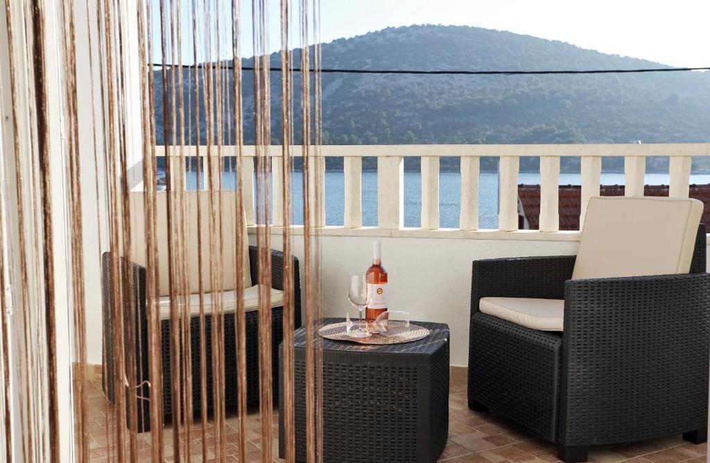 a balcony with a chair and a table with a bottle of wine at Apartments Andelic in Vinišće