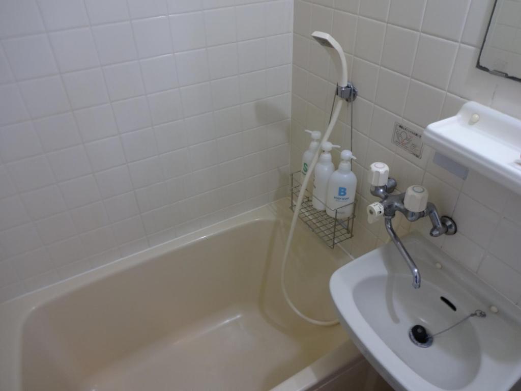 a bathroom with a bath tub and a sink at Minshuku Namisou in Iriomote