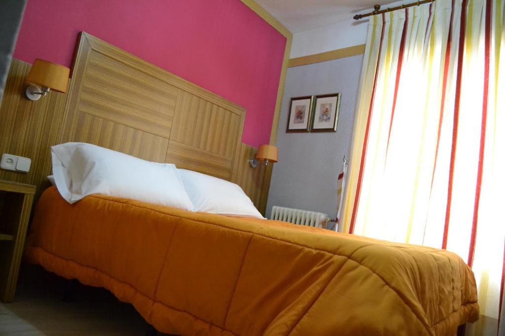 um quarto com uma cama grande e uma parede rosa em Hostal Don Juan I em Alcalá de Henares