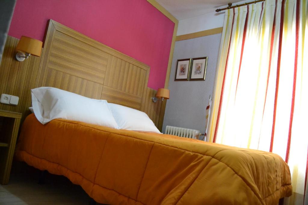 Un dormitorio con una cama grande y una pared rosa en Hostal Don Juan I, en Alcalá de Henares