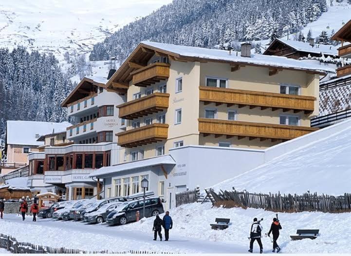 a group of people walking in the snow in front of a building at Hotel Garni Panorama in Serfaus