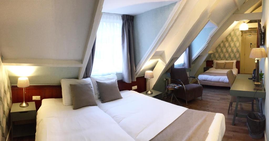 a bedroom with a white bed and a staircase at Hotel Johannes Vermeer Delft in Delft